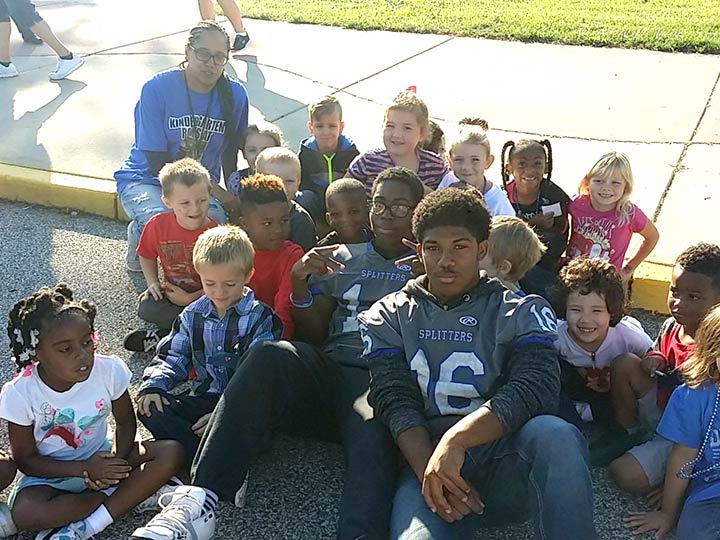Student athletes pose with elementary students at Homecoming 2016 tailgate