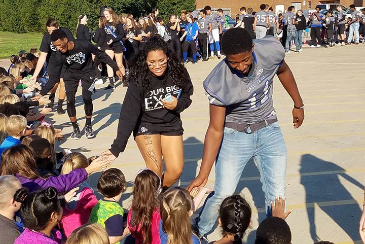 Student athletes high five elementary students at Homecoming 2016 tailgate