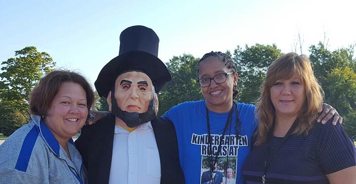 Teachers pose with Abe Lincoln Mascot at 2016 Homecoming Elementary Tailgate